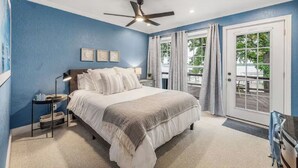 Une chambre à coucher avec un lit, un ventilateur de plafond, une table de chevet et un bureau.