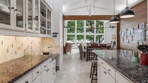 Une cuisine avec des armoires blanches, des comptoirs en granit et un coin repas avec des chaises en bois.