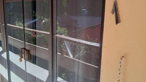 Eine Glastür mit Metallgriff, ein Holzbalkenrahmen und ein Kettenvorhang auf der rechten Seite.