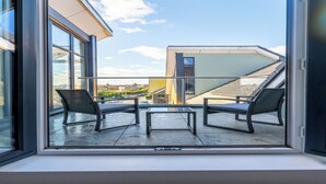 A modern building with a glass door leading to an outdoor patio with two chairs and a table. - Penthouse apartment in the centre of rayleigh - Pass the Keys (Rayleigh)