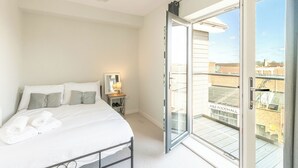 A bedroom with a bed, a nightstand, a lamp, and a sliding glass door to a balcony. - Penthouse apartment in the centre of rayleigh - Pass the Keys (Rayleigh)
