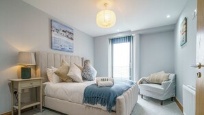 Une chambre à coucher avec un lit, une table de chevet, une lampe et une fenêtre.