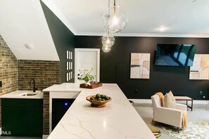 A modern kitchen with a marble countertop, a built-in oven, and a black backsplash. - BR Speakeasy Near Duke + Theatre | Sleeps 12 (Durham)