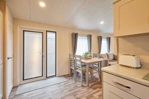 Eine kleine Küche mit Essbereich, einem Toaster und einer Schiebetür zum Balkon.