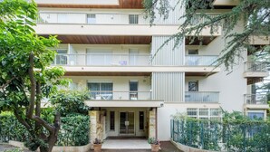 Un edificio residenziale a più piani con balconi, un ingresso centrale e vegetazione circostante.