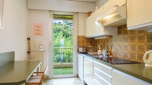 Cucina con vista sul giardino, armadietti bianchi e zona pranzo con tavolo e sedie.