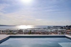 Une piscine avec vue sur la mer et sur le paysage urbain au loin.