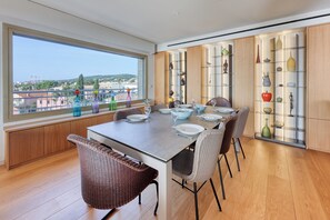 Un coin repas avec une grande fenêtre, une table dressée pour quatre personnes et une collection d’objets décoratifs.