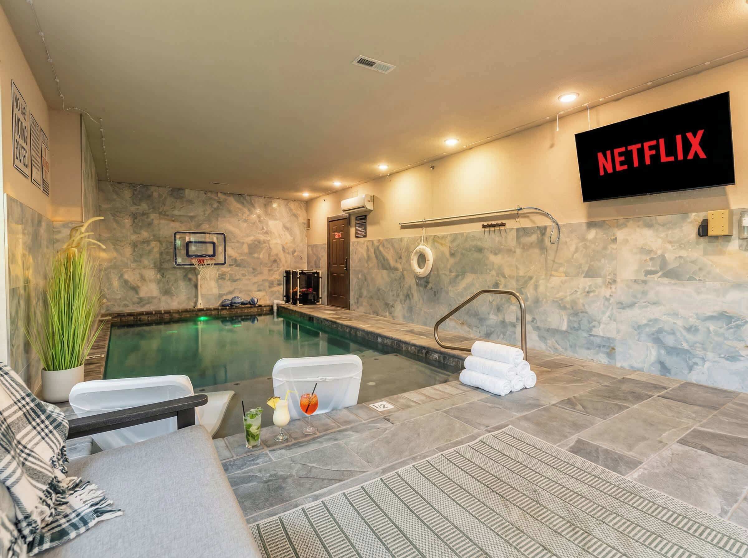 Un espace piscine agrémenté d’un panneau Netflix, d’un panier de basket et d’un porte-serviettes.