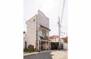 A two-story building with a gated entrance, a visible garage, and a utility pole with wires.