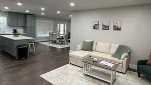 Een moderne woonkamer met een bank, salontafel en een eethoek met stoelen.