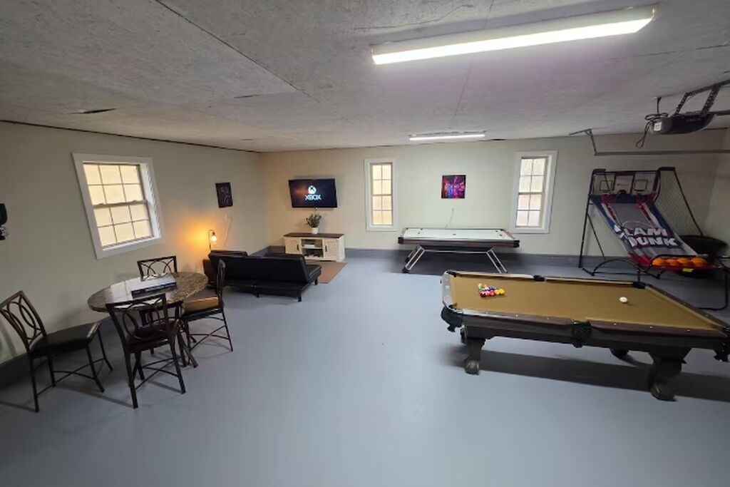Une pièce équipée d’une table de billard, d’un téléviseur, d’une table de ping-pong et d’une petite table avec des chaises.