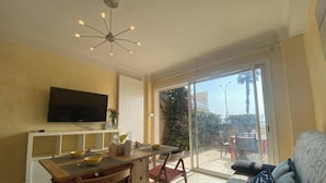 Una sala de estar con televisión, una mesa de comedor y un sofá.