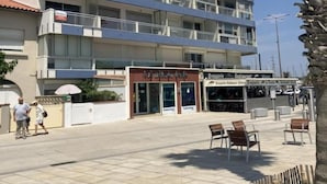 Un hotel de varios pisos con balcones, un restaurante y mesas al aire libre.