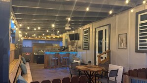 A restaurant with a bar area, wooden furniture, and hanging lights. - Cozy 2-Bedroom Retreat in Cabo Rojo Near the Beach (Cabo Rojo)