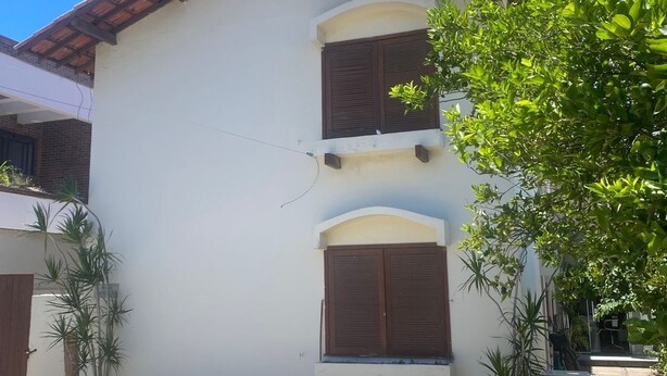 Ein eingeschossiges Gebäude mit Ziegeldach, einer kleinen Veranda und einem Fenster mit Rollläden.