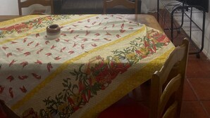 Ein Essbereich mit einem Tisch für zwei Personen, einem Deckenventilator und einem fenster mit Vorhängen.