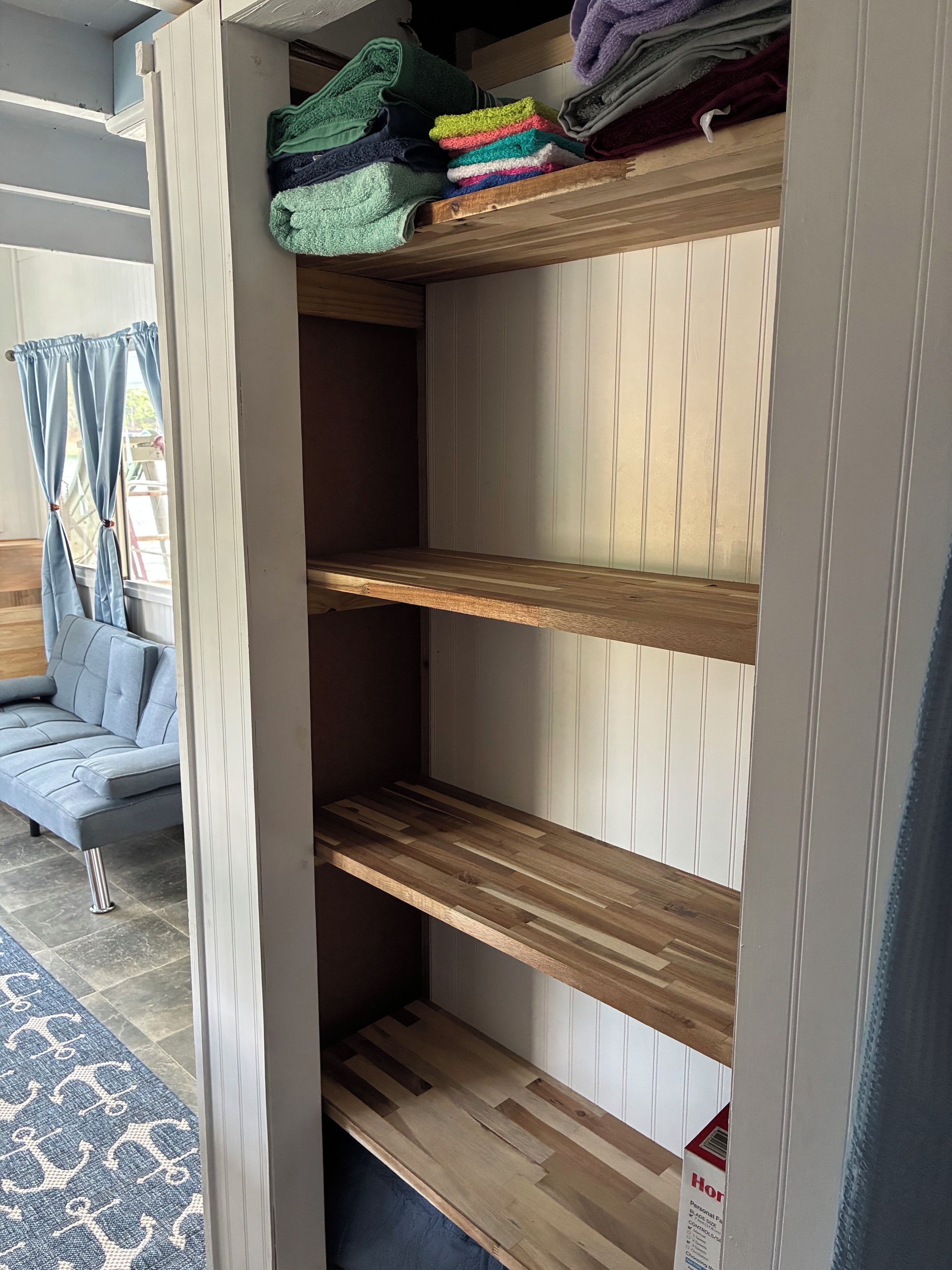 A room with a built-in wooden shelving unit, a grey sofa, and a patterned rug.