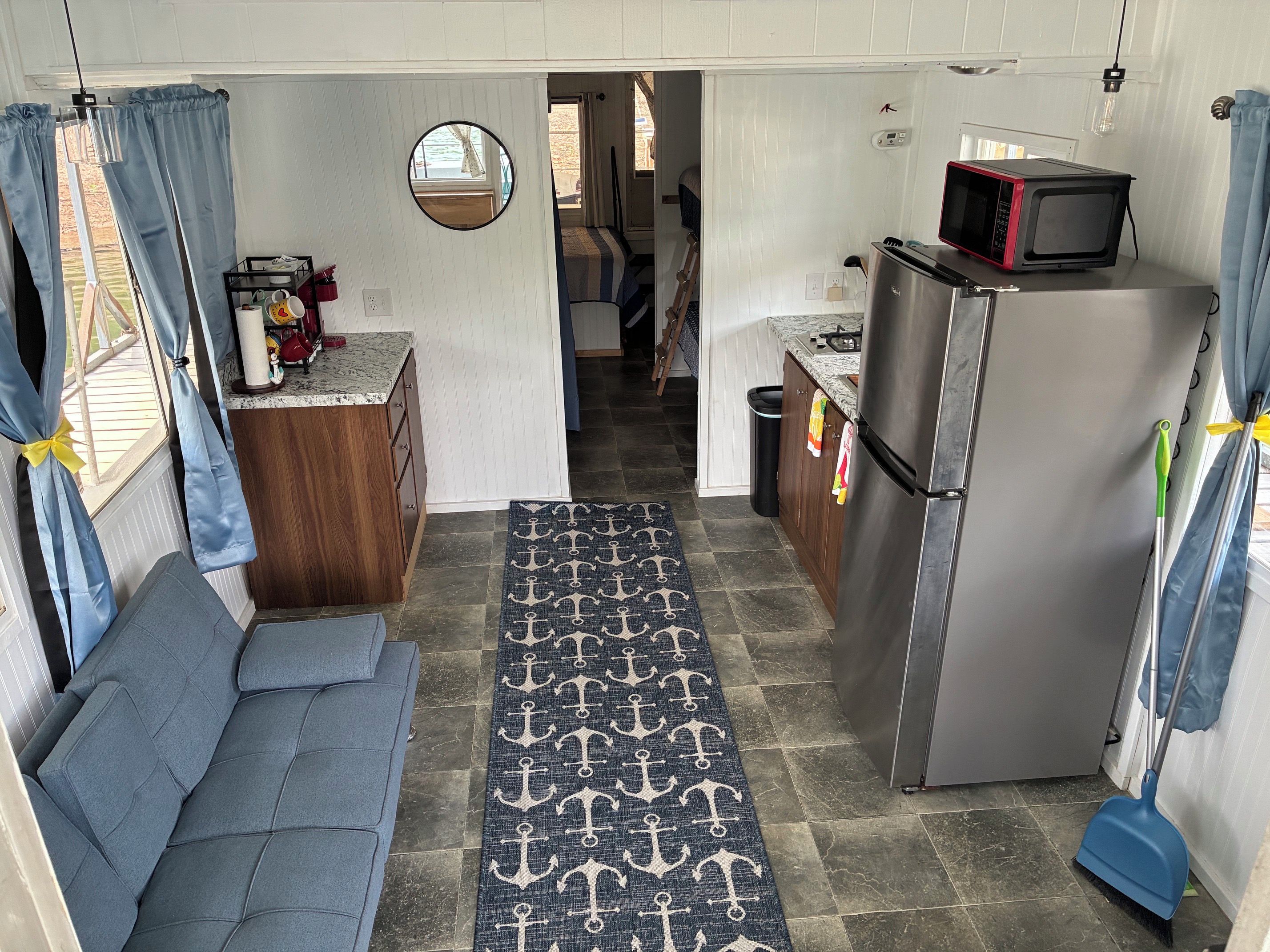 A compact kitchen with a refrigerator, microwave, and a small dining area with a bench.