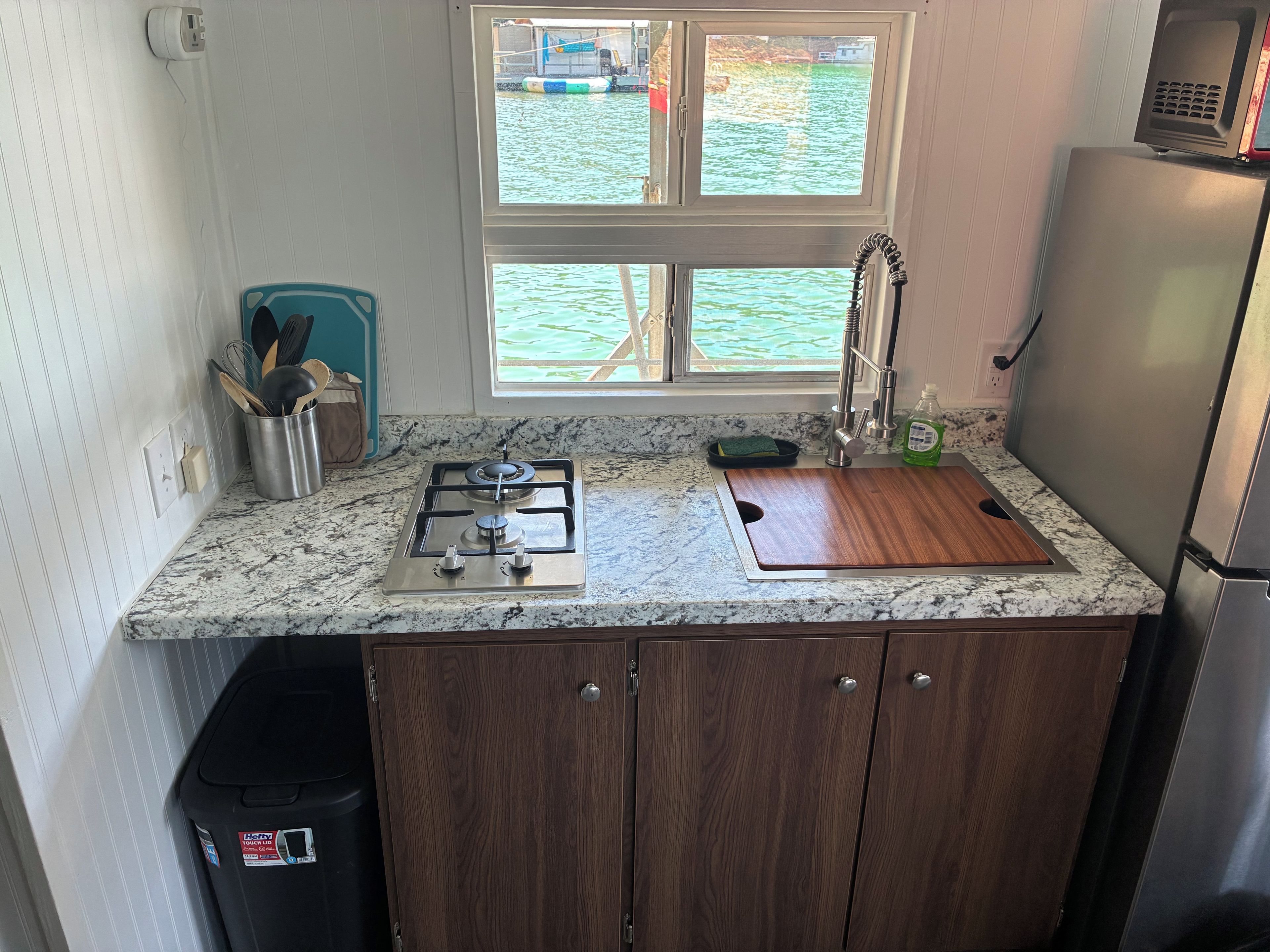 A compact kitchen with a gas stove, sink, and a refrigerator.