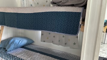 A bunk bed with a patterned headboard and a lower bed with a quilt.