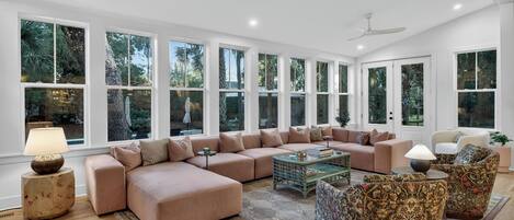 A spacious living room with a large sectional sofa, a coffee table, and patterned armchairs.