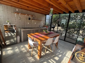 Una cocina moderna con una mesa y sillas de madera, una lámpara colgante y un ventanal con vistas a zonas verdes.