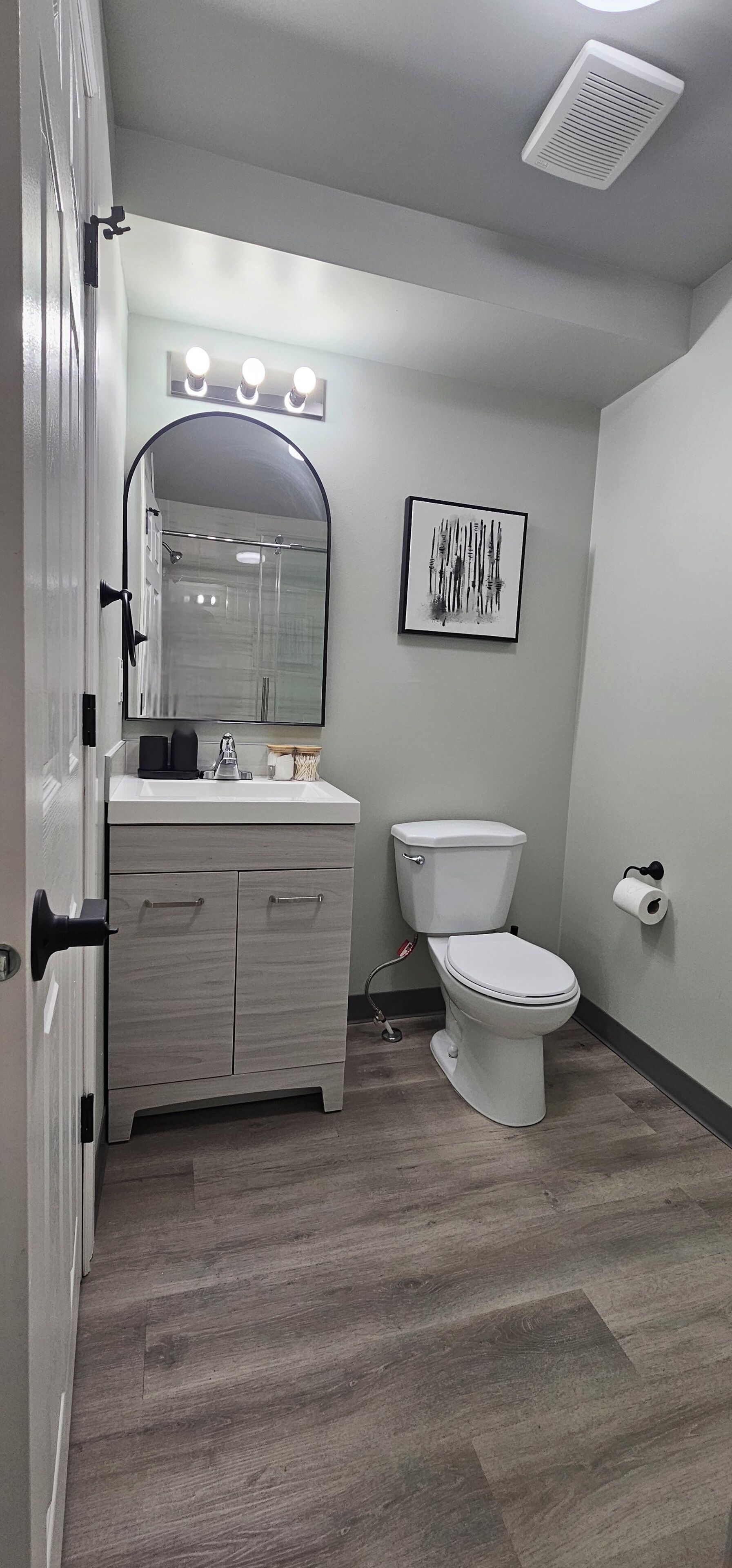 Ein Badezimmer mit Waschtisch, Toilette und einem gerahmten Kunstwerk an der Wand.