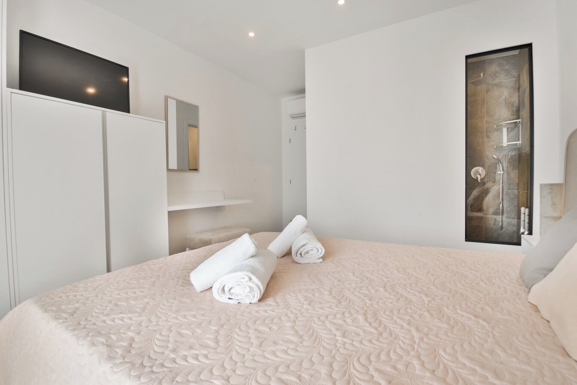 Camera da letto con un letto grande, una doccia, uno specchio e un quadro appeso al muro.