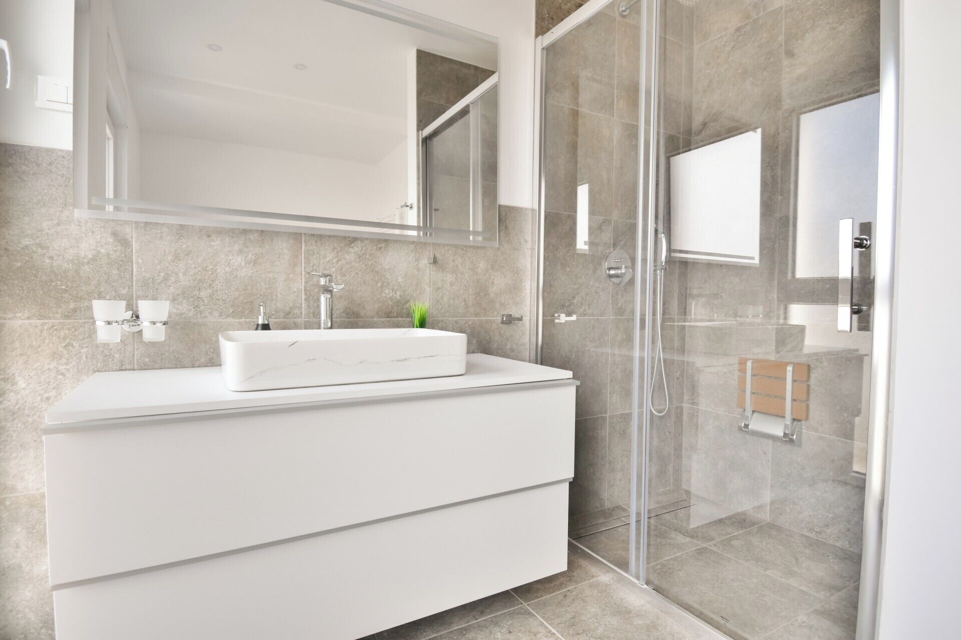 A modern bathroom with a glass shower enclosure, a white vanity with a mirror, and a tiled backsplash.