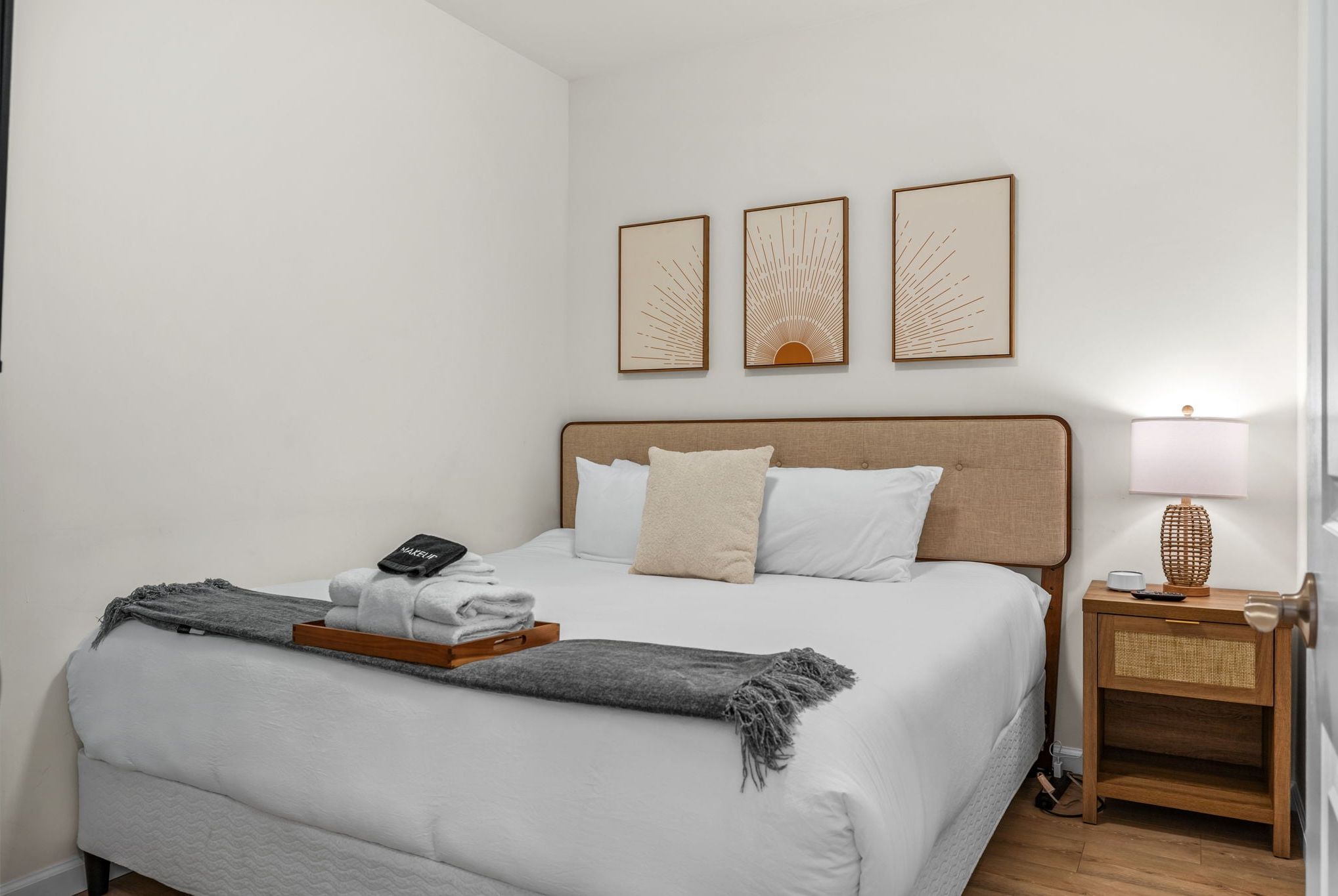 Bedroom with framed artwork, nightstand, bedside lamp, and gray throw.