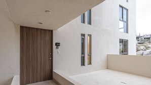 Ein modernes Gebäude mit einer Holztür, Hausnummer 101, und einem kleinen Balkon mit Blick auf die Umgebung.
