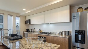 Eine moderne Küche mit einer Granit Arbeitsplatte, Edelstahlgeräten und Holzschränken.