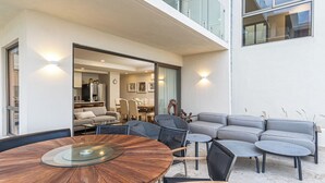 Ein moderner Außenbereich mit einem runden Holztisch, grauen Sofas und einem Essplatz.