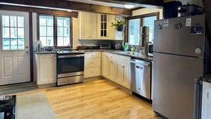 Une cuisine avec des poutres en bois, un réfrigérateur en acier inoxydable, une cuisinière et un lave-vaisselle.