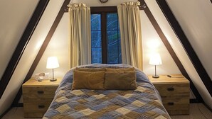 Une chambre à coucher comprenant un lit, deux tables de chevet avec des lampes, une fenêtre avec des rideaux et un élément décoratif mural.