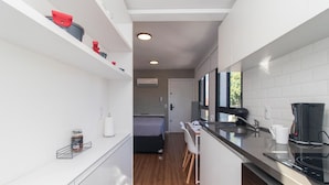 A compact kitchen with a built-in stove, a coffee maker, and a microwave. - Studio c Vaga Smart Lock e Ar no Vila Jo o Pessoa (Porto Alegre)