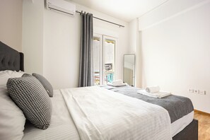 Ein Hotelzimmer mit Bett, einem fenster mit Vorhängen, einem Spiegel und einer Tür, die auf einen Balkon führt.