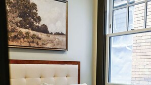 A bedroom with a bed, a window, and a painting on the wall. - Local Discounts!-The Historic Newark Arcade (Newark)