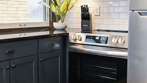 A kitchen with a stove, oven, microwave, and a window with a view of a brick wall. - Local Discounts!-The Historic Newark Arcade (Newark)