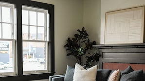 A living room with a sofa, a coffee table, a plant, and a fireplace. - Local Discounts!-The Historic Newark Arcade (Newark)