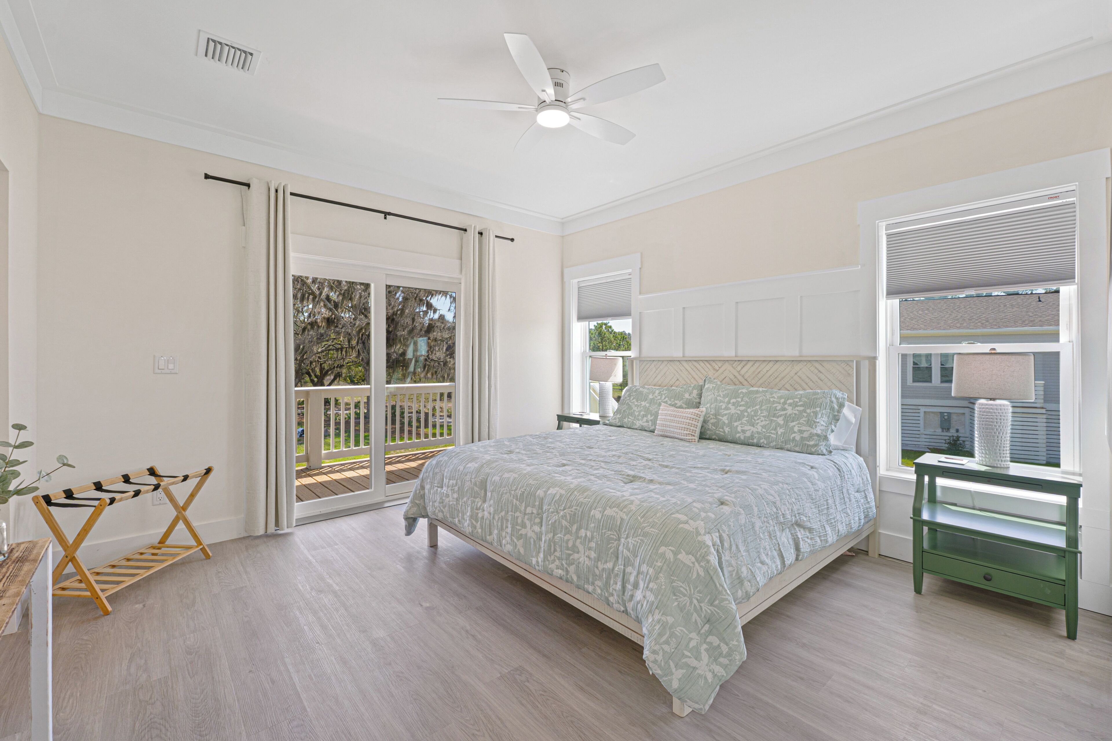 A bedroom with a bed, a ceiling fan, a window with blinds, a nightstand, and a wooden drying rack.