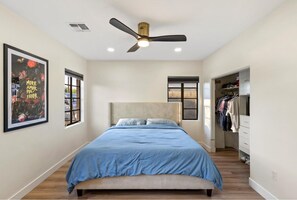 Ein Schlafzimmer mit Bett, Deckenventilator, Fenster und Schrank.