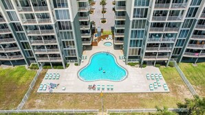 Un hotel de gran altura con una piscina central rodeada de tumbonas y un pequeño jacuzzi circular.