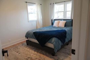 Ein Schlafzimmer mit Bett, Fenster und Tür.