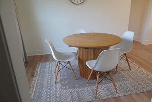Ein Essbereich mit einem runden Holztisch und vier weißen Stühlen.
