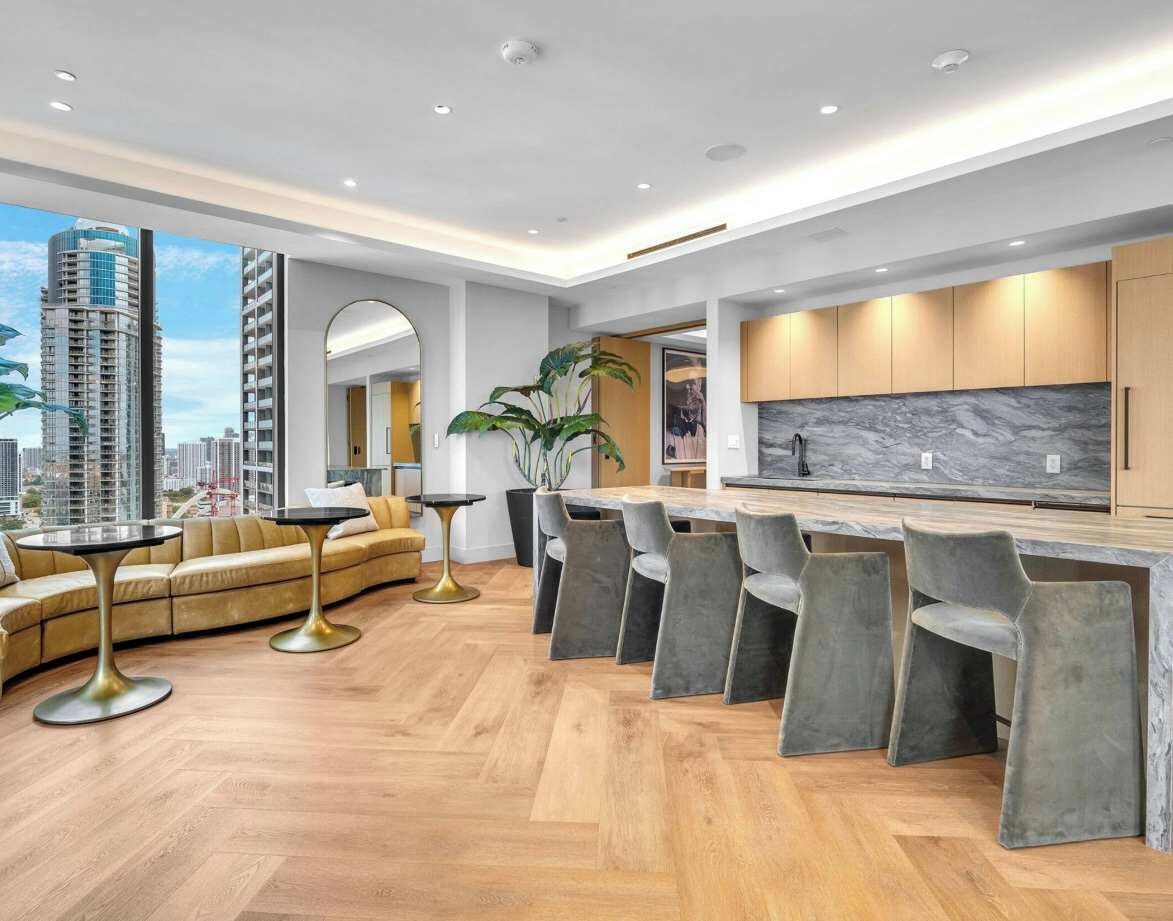 A modern kitchen with a marble countertop and a dining area with a sofa and chairs.
