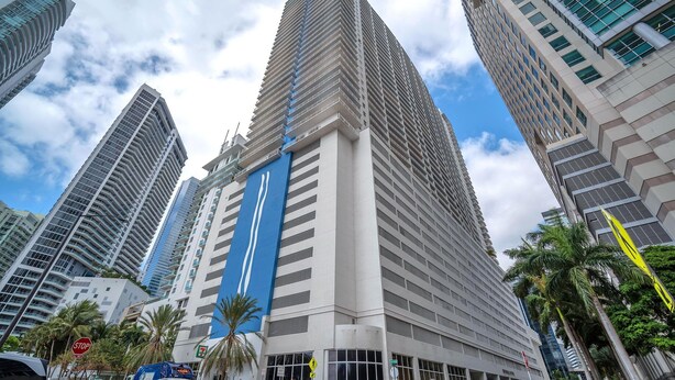 A tall, modern building with a prominent blue stripe, surrounded by other high-rise buildings. - Stylish Brickell 1BR - Free Parking - Sleeps 6 (Miami)