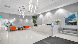 A modern reception area with a marble counter, orange seating, and a large abstract painting. - Stylish Brickell 1BR - Free Parking - Sleeps 6 (Miami)