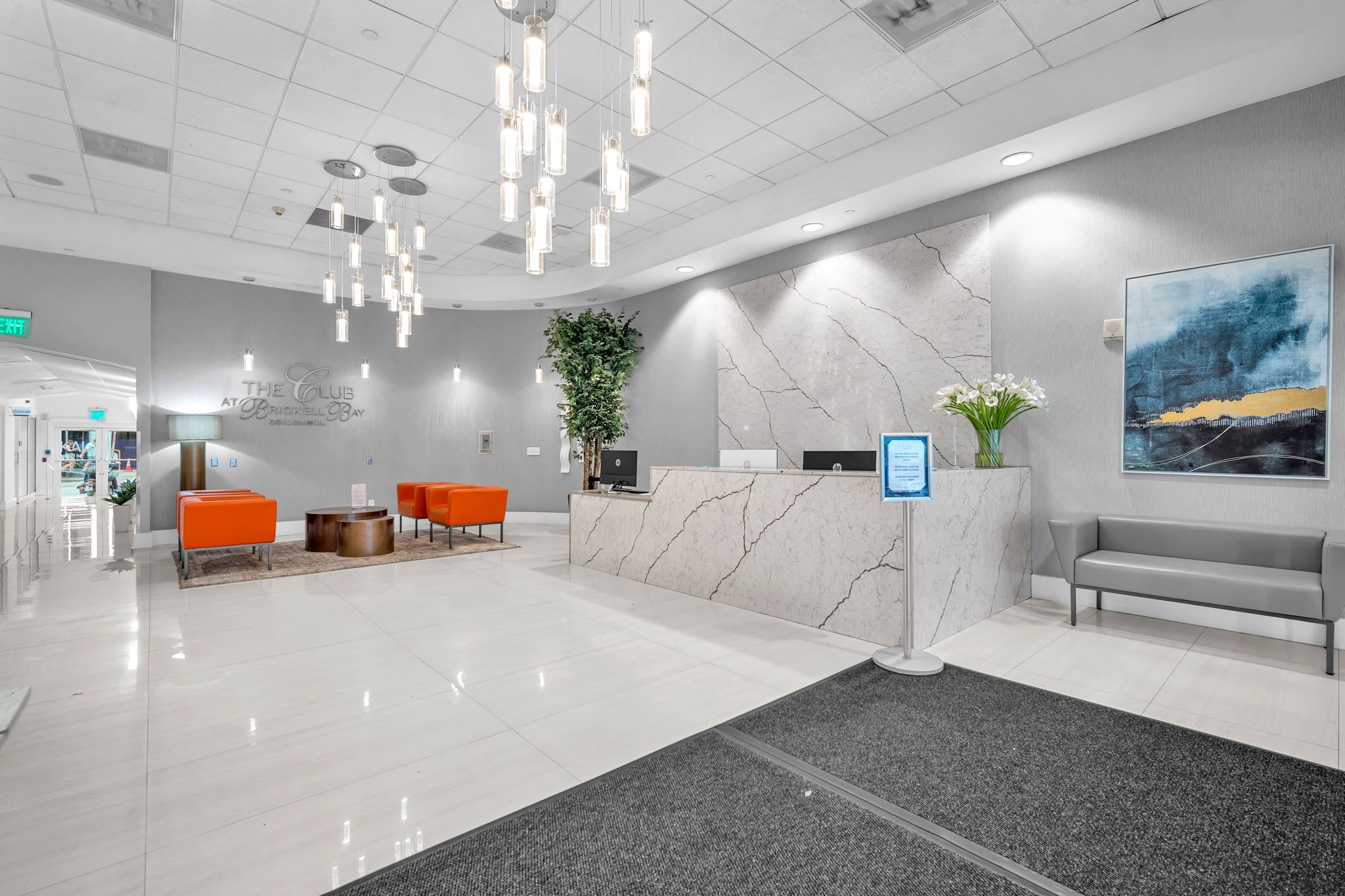 A modern reception area with a marble counter, orange seating, and a large abstract painting.